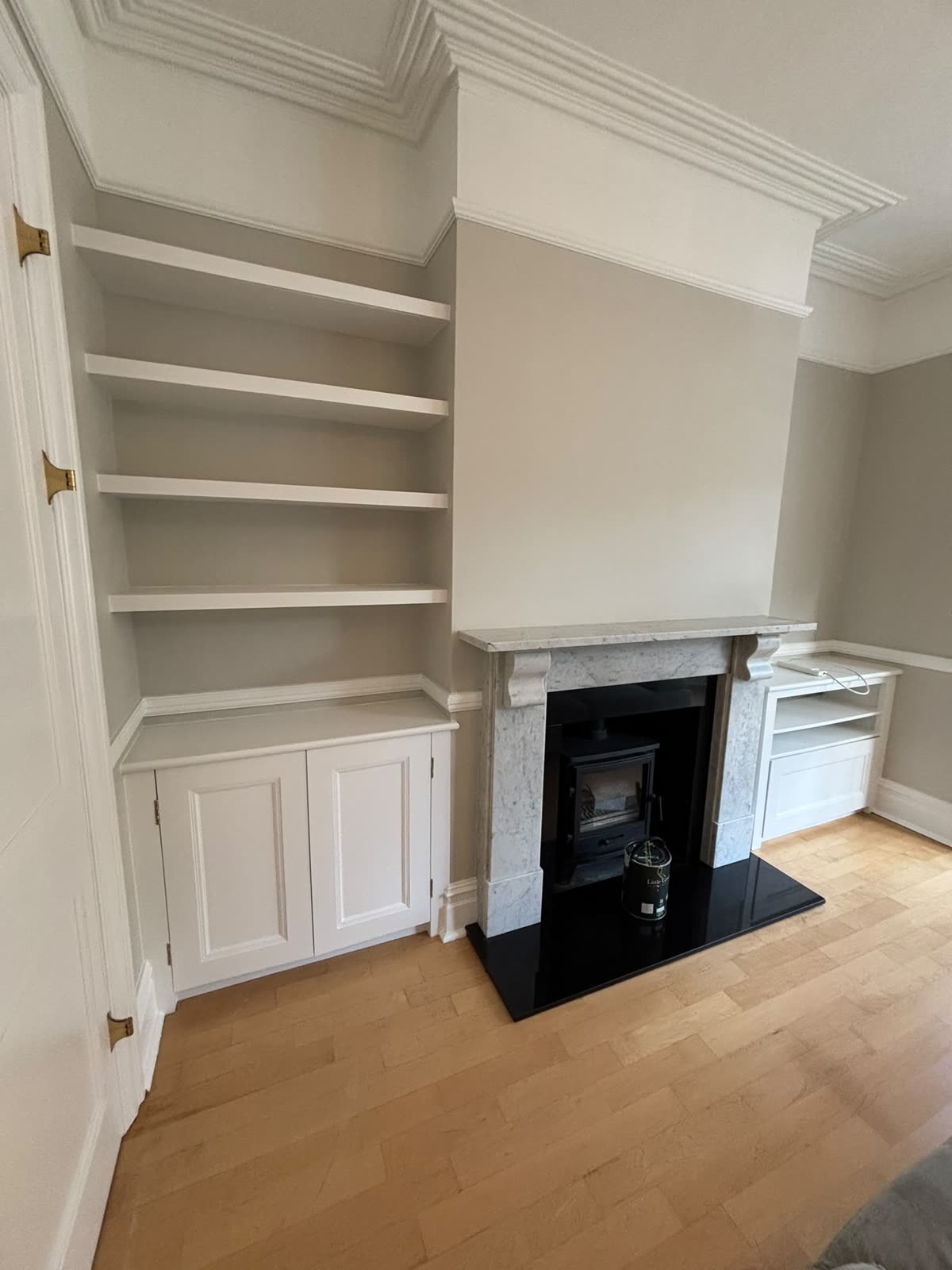 Painted alcove shelving and cupboards beside a marble fireplace